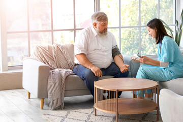 Sticker - Nurse measuring blood pressure of mature man at home