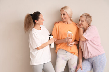 Sticker - Group of sporty mature women with water bottles on light background