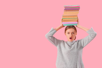 Wall Mural - Surprised female student with stack of books on his head against pink background. End of school concept