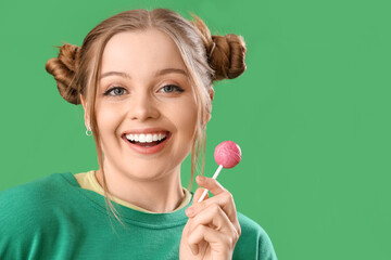 Poster - Beautiful young happy woman in stylish outfit with lollipop on green background