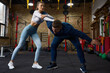Young sportive woman practicing grappling in duel with personal trainer