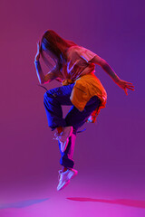 Wall Mural - Beautiful young woman dancing hip-hop on dark purple background
