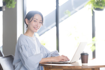 Sticker - 逆光の綺麗なオフィスやカフェでパソコンで仕事をする笑顔の美人なアジア系(日本人）女性の横顔クローズアップのビジネスシーン　カメラ目線