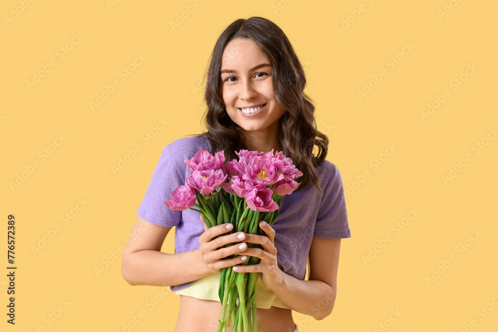 Young woman with tulips on yellow background