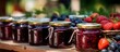 An assortment of colorful jars filled with delicious jam, surrounded by fresh strawberries and grapes on a table