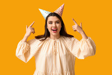 Beautiful Young Woman Pointing At Party Hats On Yellow Background