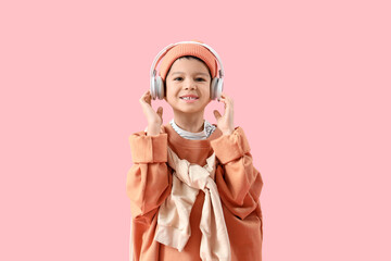 Wall Mural - Cute little Asian boy in adult clothes with headphones on pink background