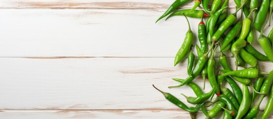 Poster - Fresh green chili peppers neatly arranged on a rustic white wooden surface for a vibrant and natural display