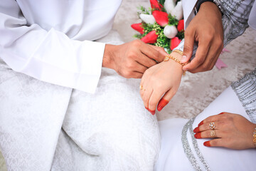 Wall Mural - Groom put a ring on finger of his lovely wife. Close up image and selective focus.