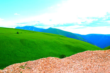 Wall Mural - Trifecta scenery near Piani di Ragnolo with a multitude of stones in the foreground, smooth green carpets of grass on mountains in the middle, and the momentous Sibillini crests in the background