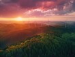 Beautiful sunset over forest with wind turbines in background