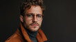 Handsome Caucasian man wearing glasses and a brown coat. It looks ahead, showcasing casual yet stylish fashion choices