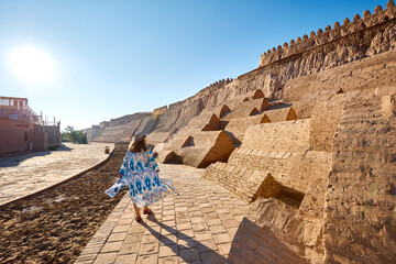 Wall Mural - Tourist woman in ethnic near city wall in Khiva