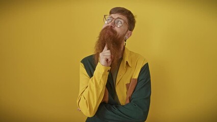 Canvas Print - Pensive young redhead man, glasses perched, chin resting on finger, standing alone in yellow. his thoughtful eyes aiming above, questioning, wondering, mulling over an intriguing puzzle.