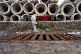 Fototapeta  - Water coming from a pipe by a pile of pipes.