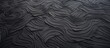 A close-up view of a smooth black surface displaying detailed and meandering wavy lines