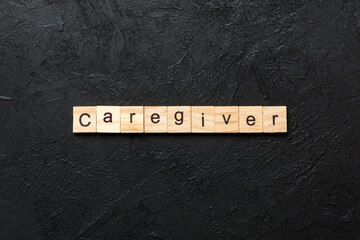 Wall Mural - Caregiver word written on wood block. Caregiver text on table, concept