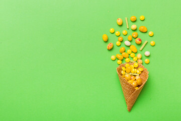 Poster - waffle cone full of assorted traditional candies falling out on colored background with copy space. Happy Holidays sale concept