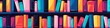 A row of colorful books neatly arranged on a bookshelf, showcasing different sizes and shapes. Banner. Copy space.
