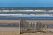 A paling fence on the beach of the North sea near to Egmond aan Zee, Netherlands, in front of a rough sea with spindrift waves