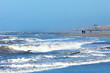 Waves in the rough North sea with some people walking along the shore