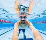 Fototapeta  - Underwater view of smiling swimmer in pool