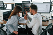 © standret - Graphs on a smartphone screen. Two employees are working in the office together
