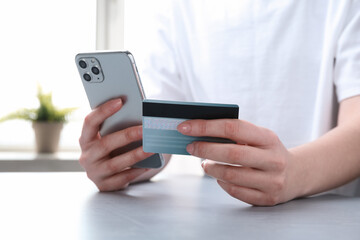 Canvas Print - Online payment. Woman with smartphone and credit card at white table, closeup