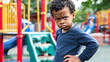 Multiracial curly hair boy wearing blue long angry or serious face hands on the hips in the playground