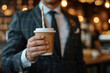 A man in a suit drinks a drink in a cup in a cafe