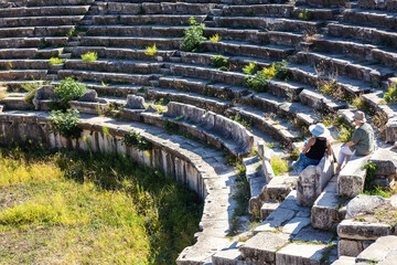 Wall Mural - Ancient Aphrodisias theater. Tourists on ancient stone seats of ruined, marble covered with greenery. Geyre, Aydin, Turkiye (Turkey)