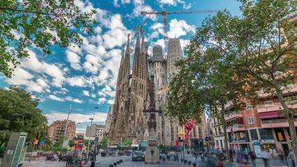 Wall Mural - Sagrada Familia Splendor: Timelapse Hyperlapse of the Iconic Catholic Church in Barcelona, Spain. Autumnal Tranquility with Green Trees and a Pensive Blue Cloudy Sky