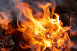 Fototapeta Miasto - Cozy orange flames lick the firewood in a burning fireplace at night