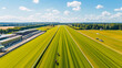 A horse race track with a green field and a few horses. The track is empty and the sky is clear