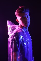 Poster - Young man wearing clear coat on dark background in neon lights