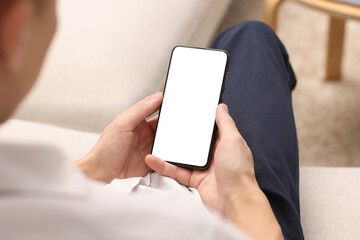 Wall Mural - Man using smartphone with blank screen indoors, closeup. Mockup for design