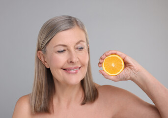 Canvas Print - Beautiful woman with half of orange rich in vitamin C on grey background