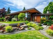 Beautiful modern home with front yard, green grass and rock garden landscape design on sunny day in the pacific northwest