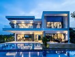 Modern contemporary two-story house with a blue tiled roof and white walls, large windows, swimming pool at night
