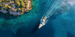 Aerial view of a luxury yacht sailing on the clear blue waters near the rocky coast