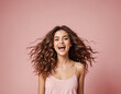 Happy excited young brunette woman on pink background