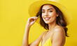 Happy smiling young beautiful woman in yellow summer dress on yellow studio background