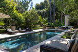 Fototapeta Natura - Inviting outdoor seating arranged around a pristine pool in a lush backyard.