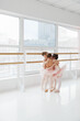 Cute little girls, ballerinas hugs in group while training near barre in light modern dance studio. Classical ballet school. Concept of art, sport, education, hobby, active lifestyle, leisure time.