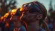 A gathering of individuals eagerly observes a solar eclipse in the park using specialized eyewear for safe viewing