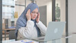 © stockbakers - Woman in Hijab having Headache while Working on Laptop