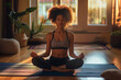 young woman sits in the living room on a yoga mat and meditates or does yoga exercises with her eyes closed and concentrates