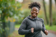 Photo of a young, happy overweight black woman running with a smile in the park, weight loss concept.