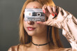 A young woman creatively obscures her eyes with a vintage music cassette tape