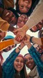 Diverse friends smiling together with hands joined in a circle looking down